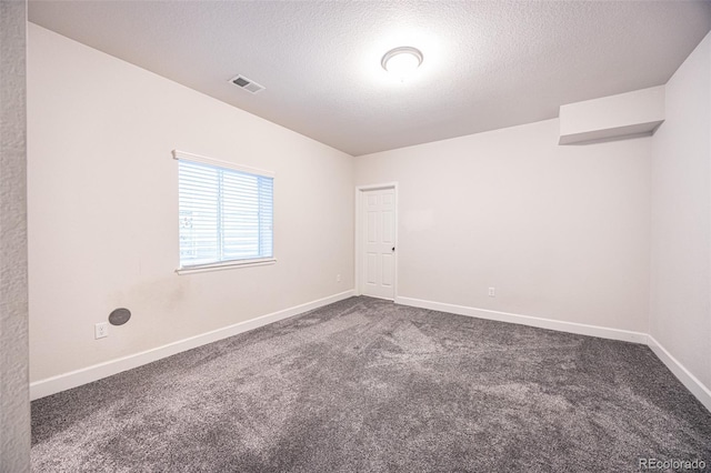 carpeted empty room with a textured ceiling and baseboards