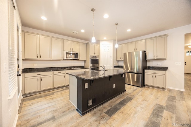 12652 Glencoe St, Thornton, CO 80241 - kitchen with appliances with stainless steel finishes, recessed lighting, dark stone countertops, a breakfast bar area, and light wood-style flooring