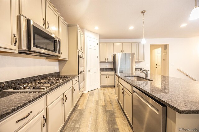 12652 Glencoe St, Thornton, CO 80241 - kitchen with stainless steel appliances, a sink, light wood-style flooring, an island with sink, and pendant lighting
