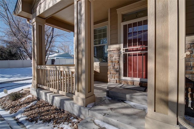 snow covered property entrance with a porch