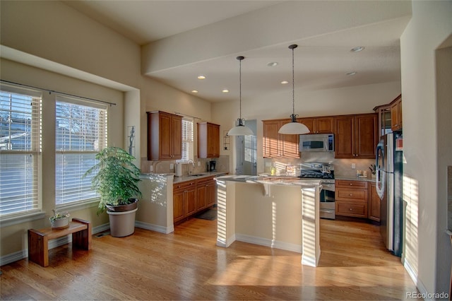 kitchen with a kitchen island, light wood-style flooring, stainless steel appliances, and a sink