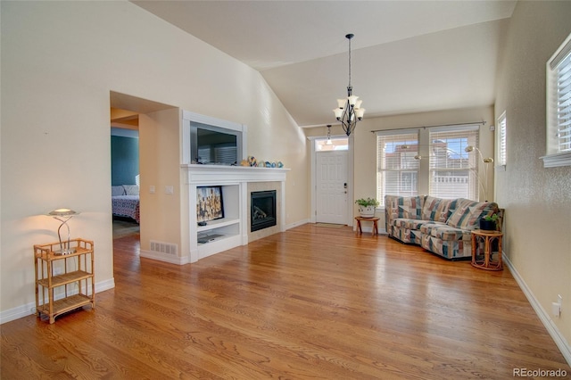 living area with visible vents, baseboards, lofted ceiling, a fireplace, and wood finished floors