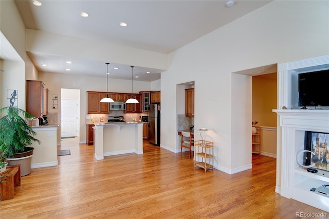 kitchen featuring brown cabinetry, appliances with stainless steel finishes, light countertops, and light wood-type flooring