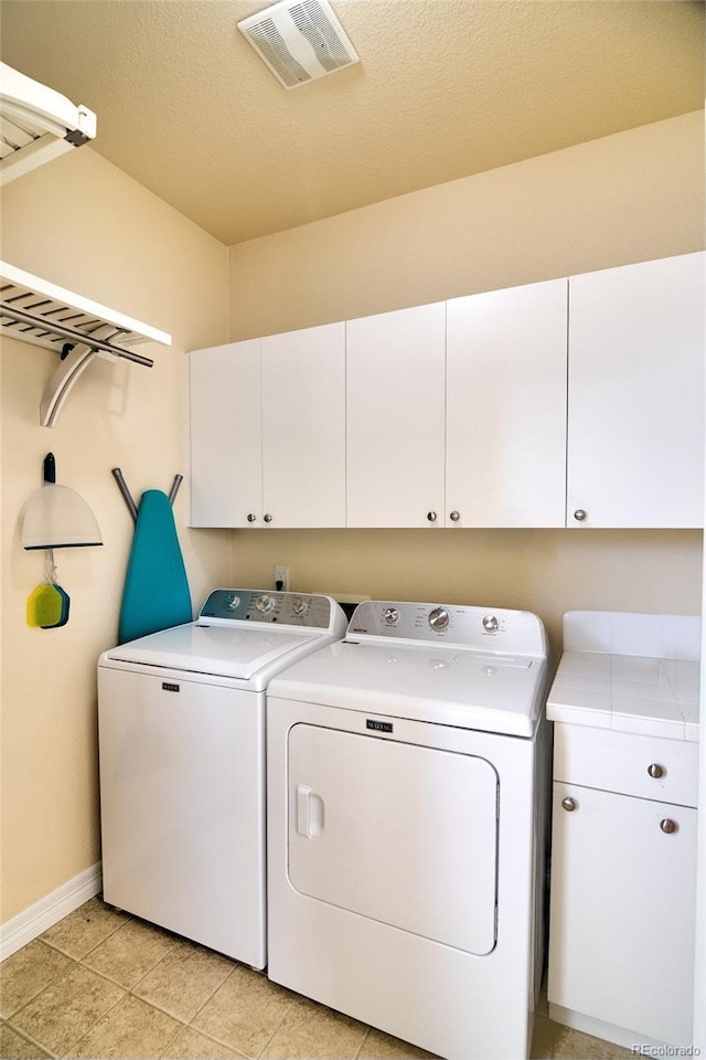 washroom featuring visible vents, baseboards, washer and clothes dryer, light tile patterned floors, and cabinet space