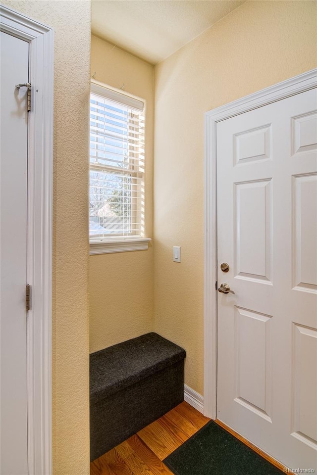 interior space featuring wood finished floors, baseboards, and a textured wall