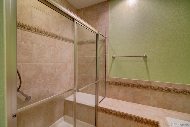 bathroom with a shower stall and a textured wall