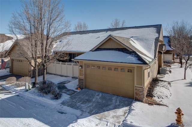 view of front of property featuring central air condition unit, fence, and stone siding