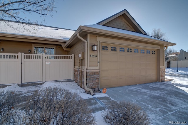 view of front of house with a gate, a garage, stone siding, and fence