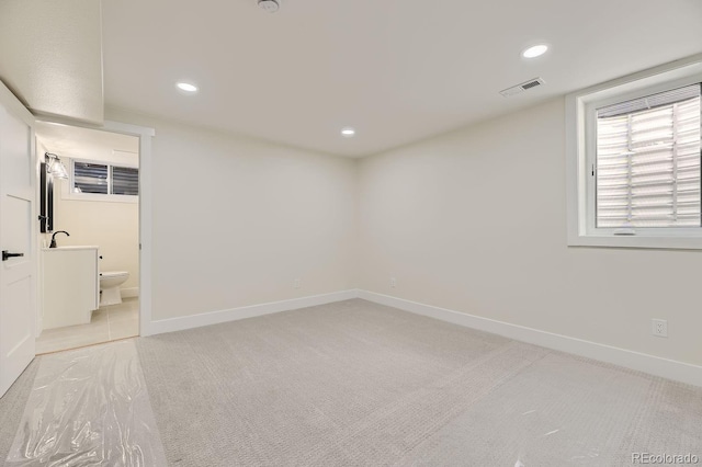 unfurnished room featuring sink and light carpet