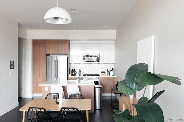 kitchen featuring brown cabinets, high end appliances, light countertops, visible vents, and an island with sink