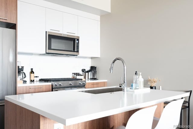 kitchen featuring appliances with stainless steel finishes, white cabinetry, a sink, and modern cabinets