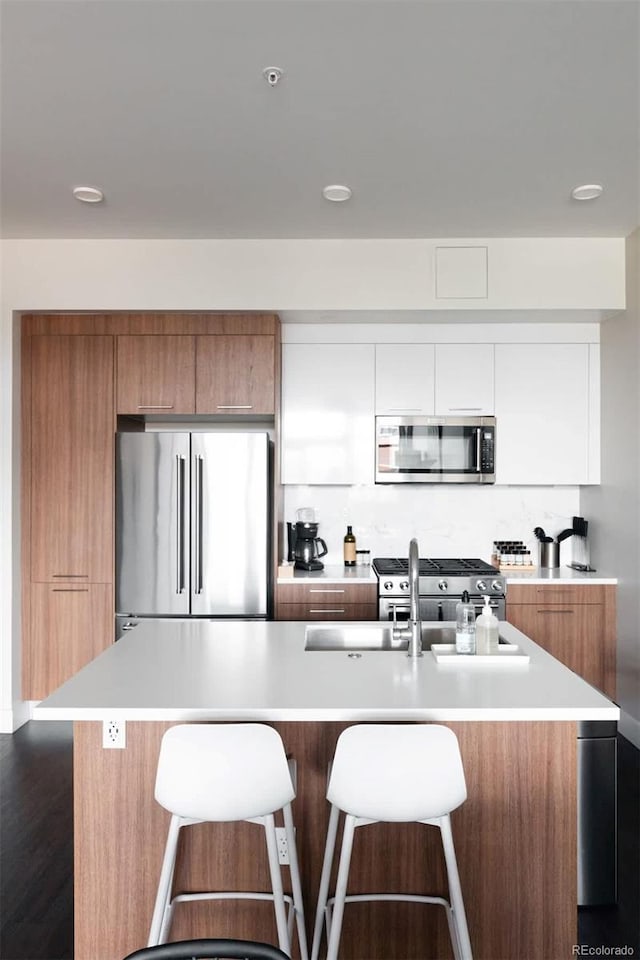 kitchen with a breakfast bar, brown cabinets, light countertops, appliances with stainless steel finishes, and modern cabinets