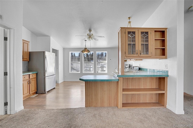 kitchen with kitchen peninsula, light carpet, a textured ceiling, ceiling fan, and stainless steel refrigerator