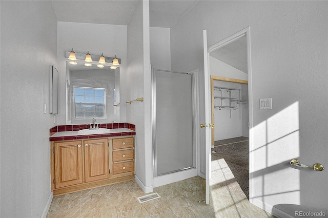 bathroom featuring vanity, a shower with door, and vaulted ceiling