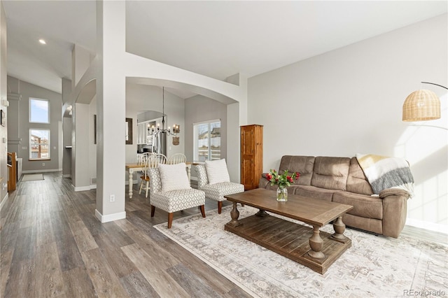 living room with an inviting chandelier, hardwood / wood-style flooring, and high vaulted ceiling