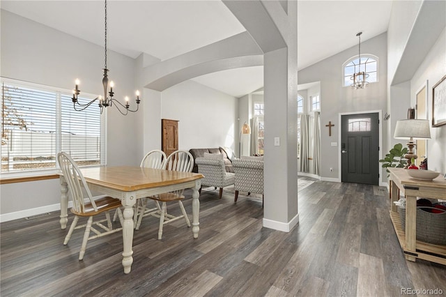 dining room featuring plenty of natural light, dark wood-type flooring, an inviting chandelier, and a towering ceiling