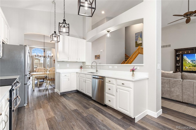 kitchen featuring stainless steel appliances, dark wood-type flooring, white cabinets, and decorative light fixtures