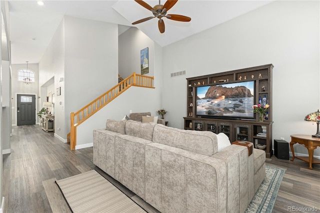 living room featuring hardwood / wood-style flooring, ceiling fan, and a towering ceiling