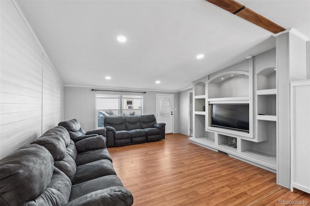 living room with built in shelves, hardwood / wood-style flooring, and ornamental molding