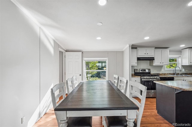 dining space with wood-type flooring, ornamental molding, and sink