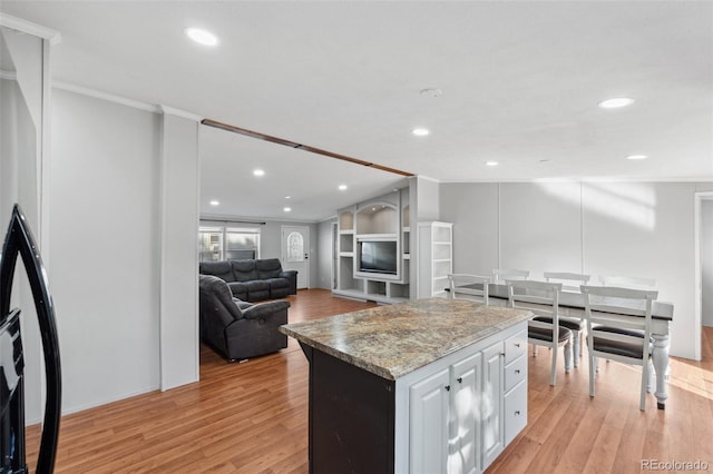 kitchen featuring ornamental molding, light stone countertops, white cabinets, and light hardwood / wood-style floors