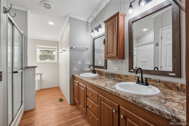 bathroom featuring wood-type flooring, a shower with door, crown molding, and vanity