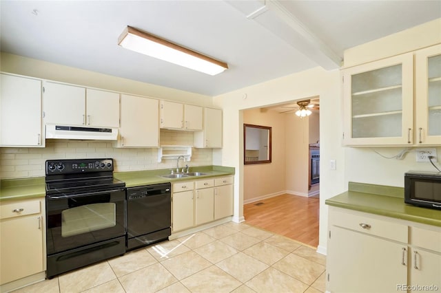 kitchen featuring glass insert cabinets, a sink, under cabinet range hood, black appliances, and backsplash