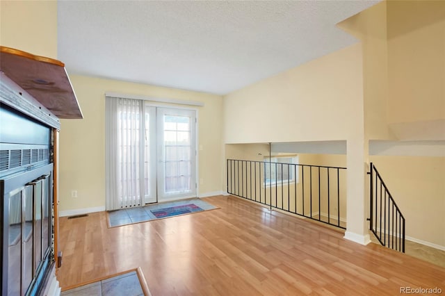 unfurnished room featuring baseboards, a textured ceiling, visible vents, and light wood-style floors