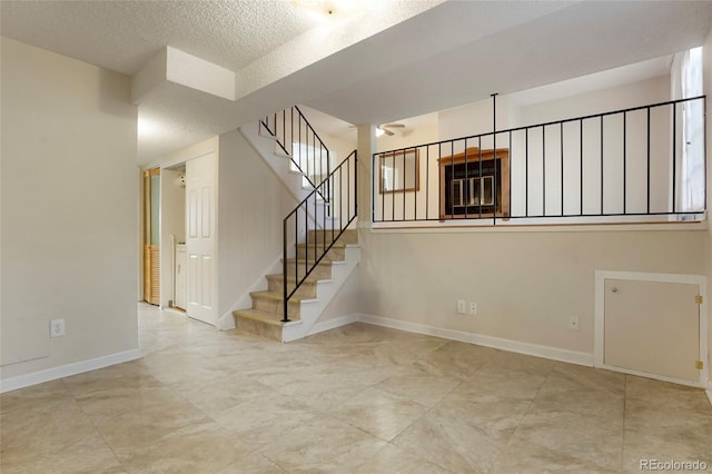 interior space with a textured ceiling and baseboards