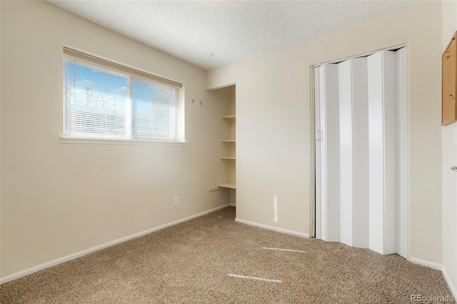 unfurnished bedroom with a closet, baseboards, a textured ceiling, and carpet flooring