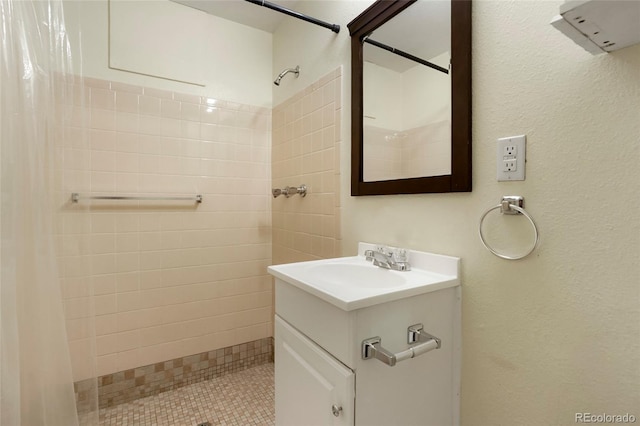 full bathroom with tiled shower and vanity