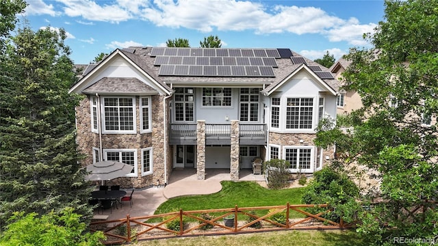 4944 W 107th Loop, Westminster, CO 80031 - rear view of house featuring stone siding, a fenced front yard, a balcony, and a patio