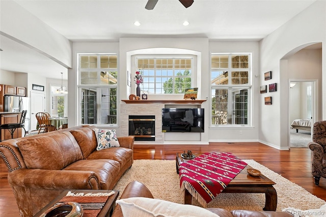 4944 W 107th Loop, Westminster, CO 80031 - living room featuring arched walkways, a ceiling fan, wood finished floors, a glass covered fireplace, and recessed lighting