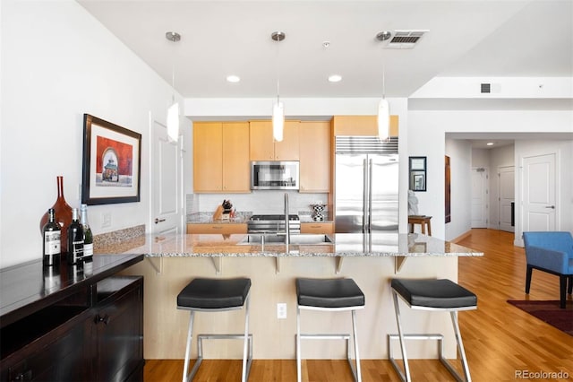 2001 Lincoln St Unit 1723, Denver, CO 80202 - kitchen featuring stainless steel appliances, light brown cabinets, a breakfast bar, decorative backsplash, and recessed lighting