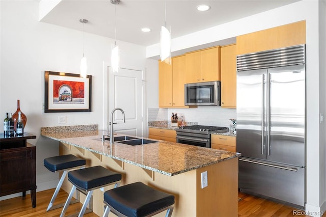 2001 Lincoln St Unit 1723, Denver, CO 80202 - kitchen with appliances with stainless steel finishes, a peninsula, wood finished floors, backsplash, and stone countertops