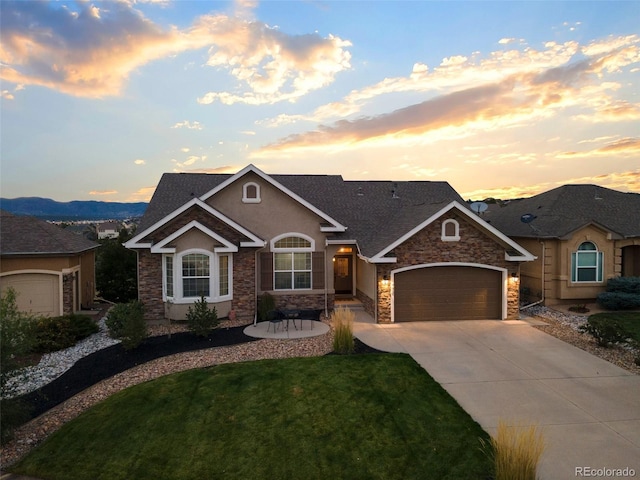 444 Pasada Way, Monument, CO 80132 - view of front of home with stone siding, an attached garage, concrete driveway, and a yard