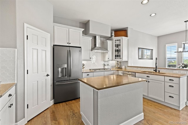 444 Pasada Way, Monument, CO 80132 - kitchen featuring appliances with stainless steel finishes, wall chimney range hood, a sink, a peninsula, and light wood finished floors