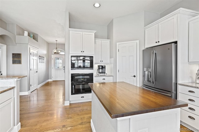 444 Pasada Way, Monument, CO 80132 - kitchen with stainless steel fridge with ice dispenser, white cabinetry, light wood finished floors, a kitchen island, and baseboards