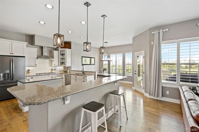 444 Pasada Way, Monument, CO 80132 - kitchen with stainless steel appliances, wall chimney exhaust hood, a large island, recessed lighting, and a breakfast bar