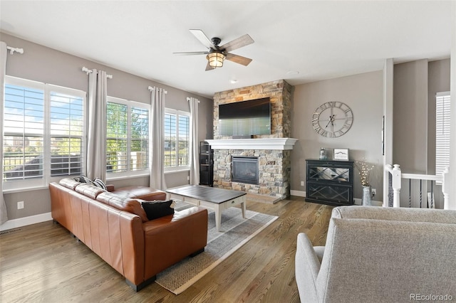 444 Pasada Way, Monument, CO 80132 - living area featuring a stone fireplace, ceiling fan, baseboards, and light wood-style flooring