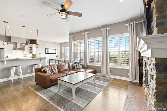 444 Pasada Way, Monument, CO 80132 - living room with a stone fireplace, a ceiling fan, dark wood-style floors, plenty of natural light, and recessed lighting