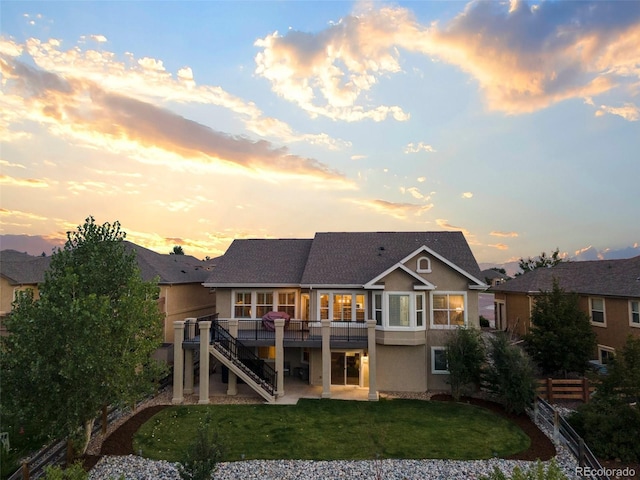 444 Pasada Way, Monument, CO 80132 - back of property at dusk featuring stucco siding, stairway, a wooden deck, and a patio