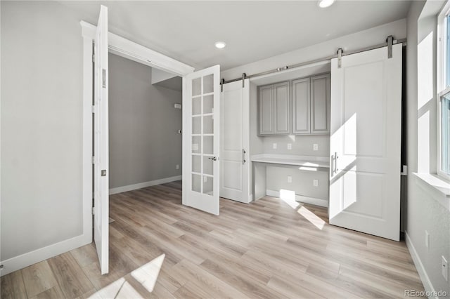 unfurnished dining area featuring a barn door and light wood-type flooring