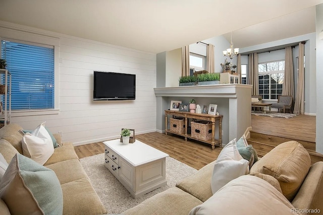 5414 Brookline Dr, Timnath, CO 80547 - living room with light wood-style flooring, a chandelier, baseboards, and wood walls