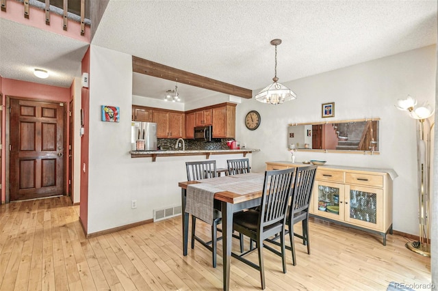 1950 S Helena St Unit D, Aurora, CO 80013 - dining area with a chandelier, a textured ceiling, light wood-type flooring, and baseboards