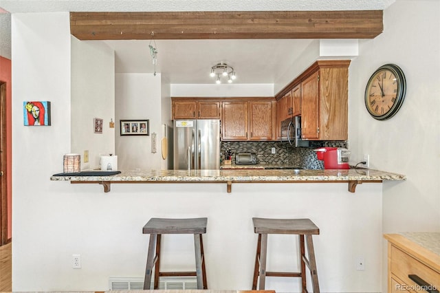 1950 S Helena St Unit D, Aurora, CO 80013 - kitchen with freestanding refrigerator, decorative backsplash, light stone countertops, and a peninsula