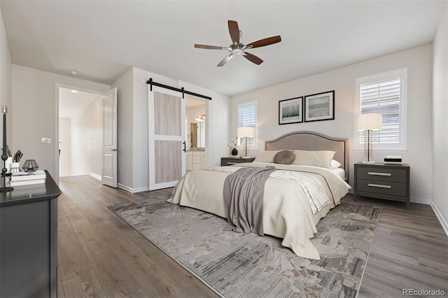 11896 Meade Ct, Westminster, CO 80031 - bedroom featuring a barn door, wood finished floors, ceiling fan, and connected bathroom