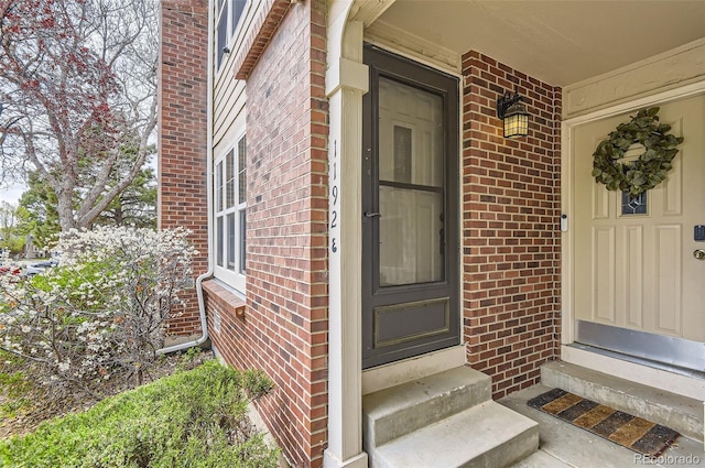 entrance to property with a porch and brick siding