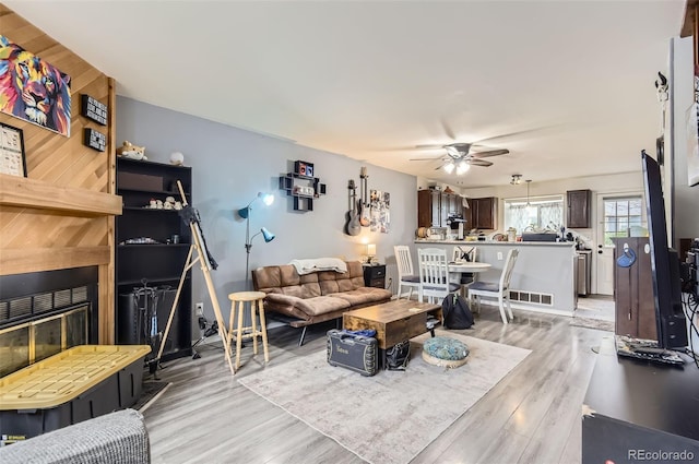 living area with visible vents, a ceiling fan, and light wood finished floors