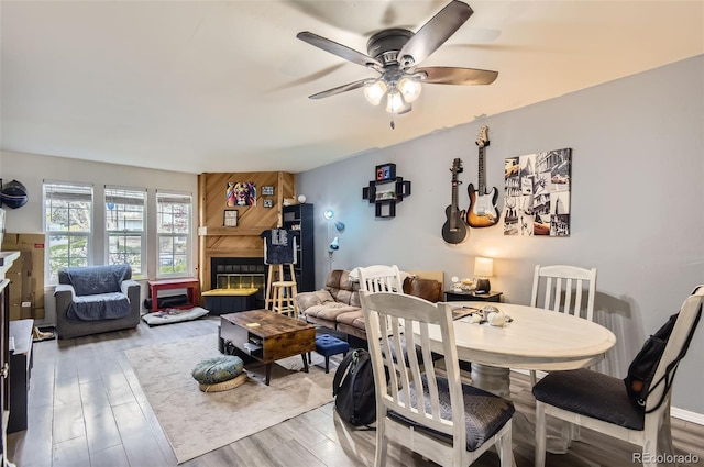 dining space featuring a ceiling fan, wood finished floors, and a fireplace